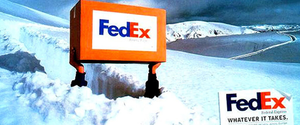 A FedEx package is being held above deep snow by two hands, with snow-covered mountains in the background. To the right, a FedEx sign displays the slogan "WHATEVER IT TAKES." The sky is cloudy with a hint of blue, creating a perfect backdrop for your next PowerPoint slide.